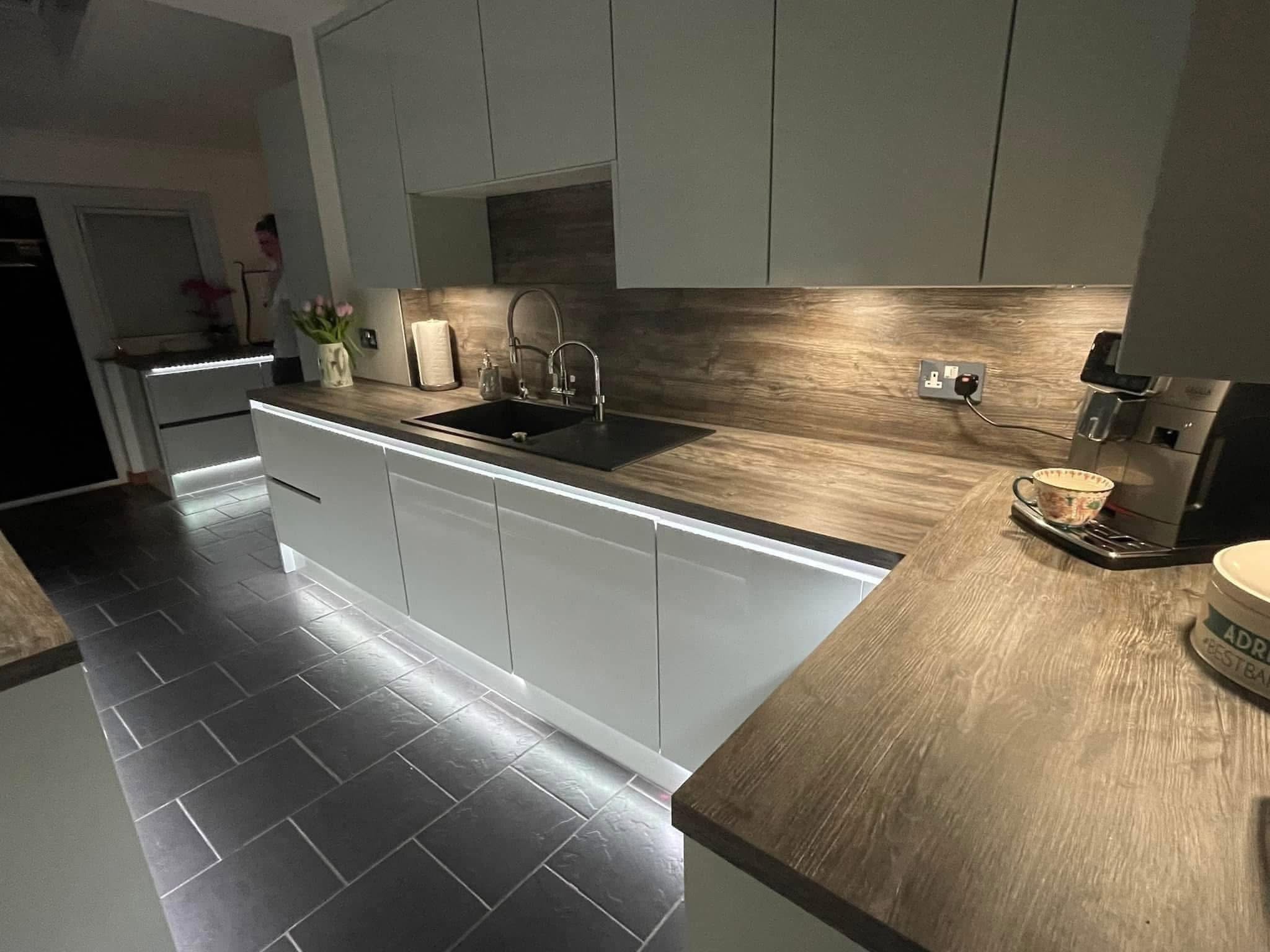 Modern grey kitchen with wood effect worktop, sink and LED lighting