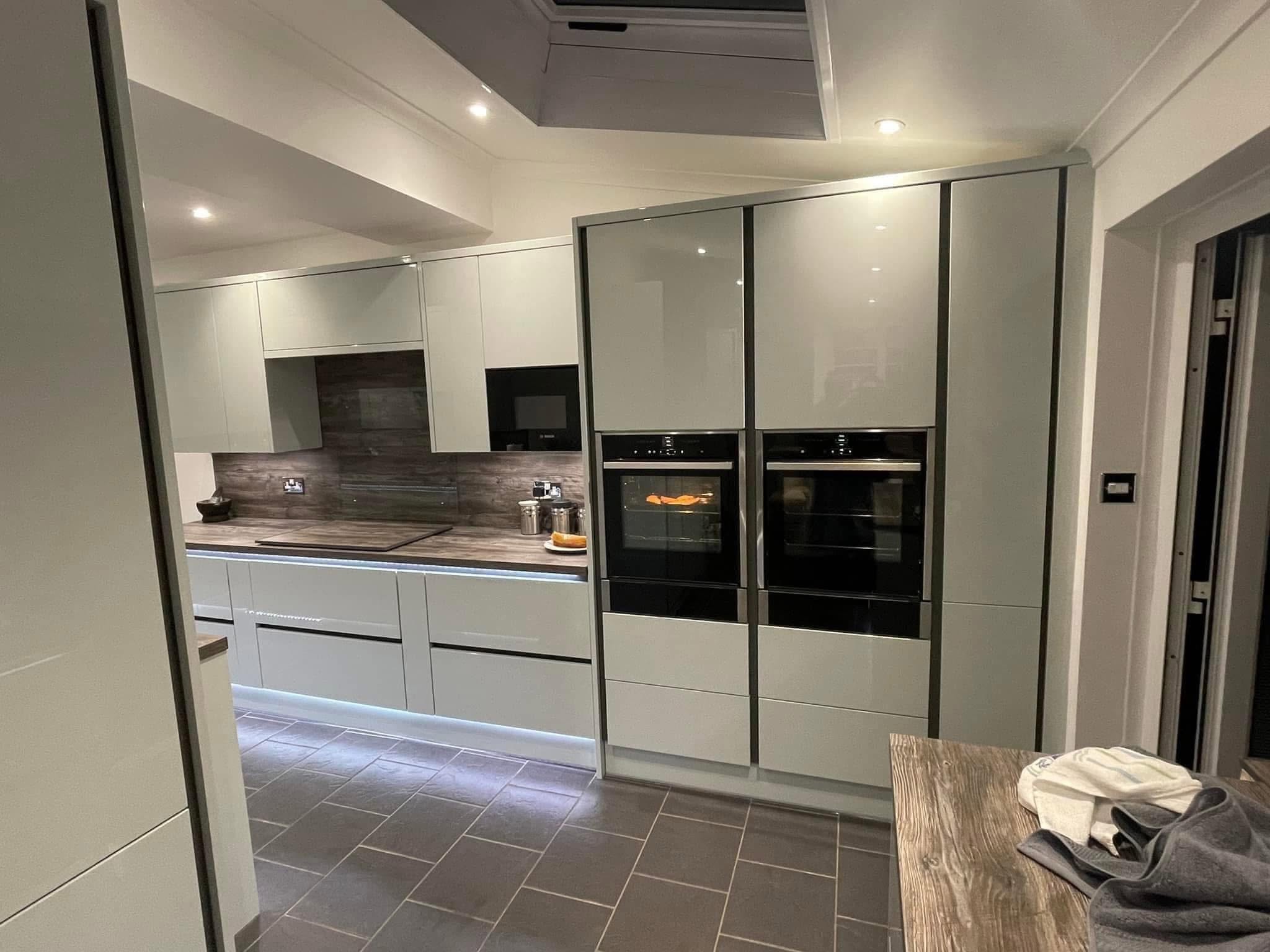 Modern white kitchen with LED plinth lighting and double ovens